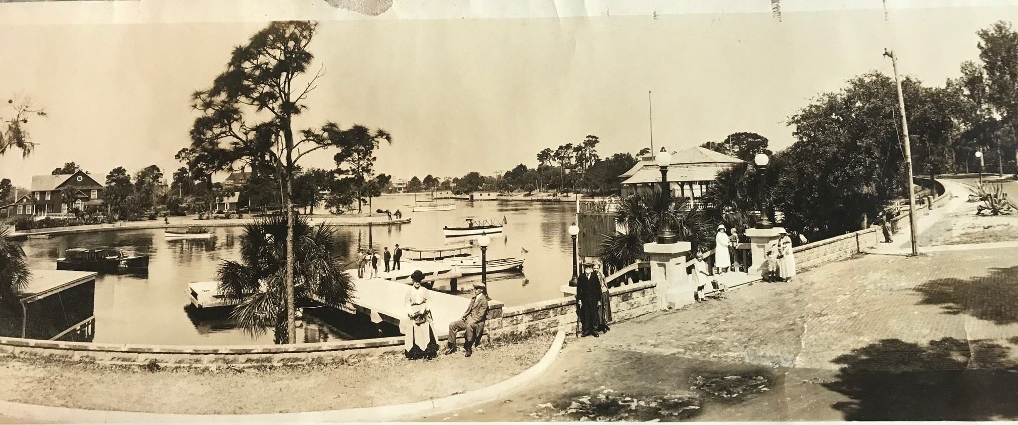 Historic picture of Spring Bayou with people sitting along the seawall and boats on the water